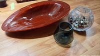 Photo showing all three bowls on a wooden table, including the large reddish-brown rose bowl, the smaller dark grey glass bowl, and the clear bowl filled with artificial berries.