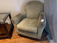 Front and side view of the olive green upholstered armchair showing fabric wear on armrests and seat cushion