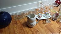Photo showing ceramic Hot Chocolate pitcher, round blue vase, glass serving tray with three glass cloches, and assorted glasses including champagne flutes and port glasses.