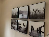 Six square black and white photo prints framed in black, hung on wall in two rows of three. Each print is 10x10 inches, showing natural landscapes and scenes including forests, waterways, grasses, and piers.