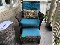 Front view of wicker armchair and footstool on tiled porch