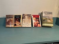 Five classic novels arranged side by side on a teal surface against a blue wall, showing all front book covers clearly.