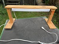 Front and top view of the homemade grow lamp showing wooden frame and fluorescent light tube beneath top board.