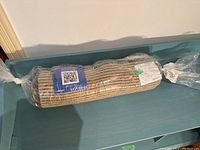 MCM wall hanging/rug rolled and wrapped in plastic packaging.