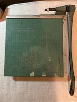 Top-down view of the square paper cutter showing the green grid surface, signs of wear and scratches