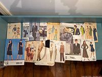 Photo showing 12 sewing pattern envelopes arranged on a flat surface. Patterns include designs by Anna Sui, Vogue, Calvin Klein, and others, featuring both men’s and women’s apparel.