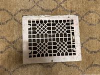 Front view of the Victorian cast iron register cover showing the geometric lattice pattern and wear on paint.