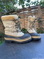 Pair of women’s Sorel Caribou boots shown on outdoor surface, front and side view to display overall condition and style.
