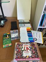 Photo shows Crayola colored pencils, marker sets, two mosaic pattern coloring books, The Incredible Clay Book, and a lap desk on a wooden surface.