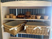 Photo of two large fabric-lined wicker baskets on bottom shelf and seven smaller wicker baskets on top shelf, showing variety of sizes and shapes.