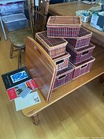 Photo of seven stacked wooden lidded boxes, Levenger wooden adjustable lap desk leaning on boxes, address book, note pads, and map on table.