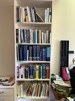 Full view of the bookcase with shelves containing dictionaries, language, encyclopedias, and religious reference books.