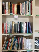 Shelf view showing another set of books including fiction and non-fiction, fiction authors visible, medical and reference titles also present, mostly hardcover.