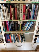 Multiple shelves filled with assorted books mostly paperback with some hardcovers, showing various titles and authors including 'Holy Terror', 'Osler's Web', and 'Leviathan'.