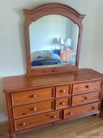 Full view of Broyhill solid wood dresser with attached large arched mirror, showing 8 drawers with wooden knobs.