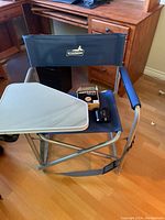 Full view of Broadstone metal and canvas folding chair with attached side table and nylon carry strap, and Nikon binoculars placed on the chair seat.