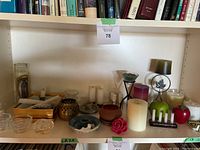 Shelf displaying various candle holders, decorative candles, and Origins oils with books behind