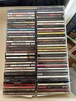 Image showing two stacks of music CDs with visible titles from artists such as Leonard Cohen, Tom Waits, Suzanne Vega, Sade, Gordon Lightfoot, and others.