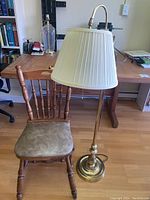 Wooden chair with brass floor lamp next to desk on wooden floor