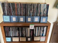 Full lot of New Yorker magazines neatly arranged in six blue magazine holders on top shelf and mixed-color holders on lower shelf