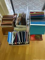 View of hanging file folders organized in cardboard magazine holders and binders in box