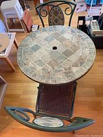 Full view of the round outdoor bistro table top and two chairs showing river rock mosaic and woven seats