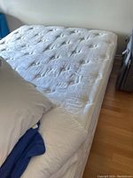 Full view of mattress and box spring on hardwood floor with pillow partial view