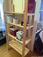 Front and side view of wooden shelf unit with four adjustable shelves. Various items on shelves for display only, not included.