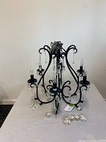 Full view of chandelier lying on table showing six arms, glass prisms, detached crystals
