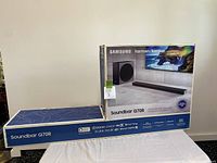 Two sealed Samsung HW-Q70R retail boxes on table