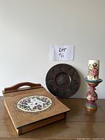 Photo of the closed folk art writing lap desk, round wooden platter, and folk art candle with stand arranged in a row.