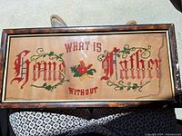 Frontal view of entire needlepoint framed artwork showing phrase and damage