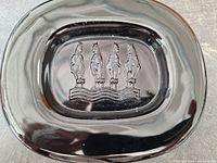 Top view of heavy black Murano glass dish depicting embossed equestrian horses in relief on the flat center surface.