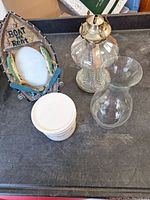 Photo shows boat photo frame, glass oil lamp, clear glass vase, and white ceramic crock base with lid.