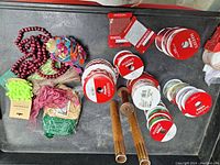 Photo showing various colorful Christmas ribbon rolls, red beaded trim, and multicolored yarn trims with two antique wooden spools.