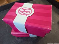 Two stacked pink Marie Osmond doll boxes with white bands and Marie Osmond logo on top.