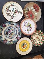 Photo showing all six plates arranged in a group to display varied floral and bird designs.