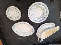 Overhead view of all pieces showing bowls, saucers, serving dish, and gravy boat with blue floral pattern on white ceramic.