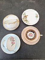 Four vintage teacups each with matching saucers in various floral and gold trimmed patterns.