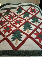 Christmas-themed quilt with tree and star blocks in red, green, and white, showing front pattern.