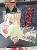 Full lot showing ties, scarves, handkerchiefs, and decorative pouch arranged on gray surface.