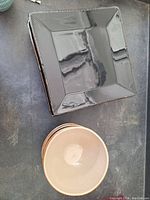 Photo showing square black plate and beige bowl side by side