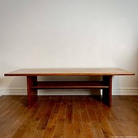 Front view of teak coffee table showing rectangular top and lower shelf