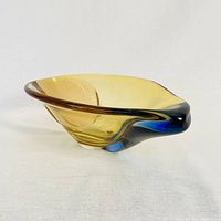 Side angled view showing the curved amber-yellow glass transitioning to brown and blue edges of the bowl on a white background.