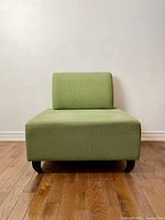 Front view of sage green modular sofa chair showing square seat cushion, backrest and curved wood legs against neutral background.