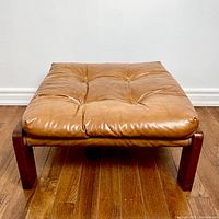 Front-left perspective showing tufted leather cushion and wood frame