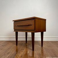 Front left three-quarter view of walnut side table with single drawer and tapered legs