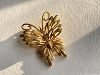 Front view of vintage gold tone butterfly brooch pin, showing detailed cutout wing design and shiny finish.