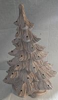 Full view of ceramic Christmas tree with textured branches and numerous light holes, showing gold shimmer finish.