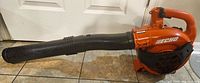 Full side view of the orange Echo leaf blower with black tube attachment to show overall condition and model visible.